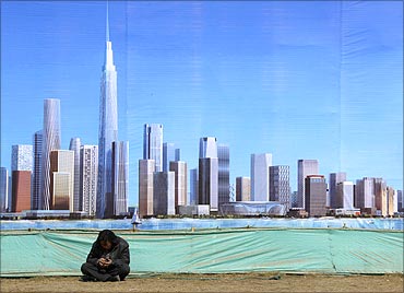 A worker rests in front of an artist's impression of the new business district of Binhai.