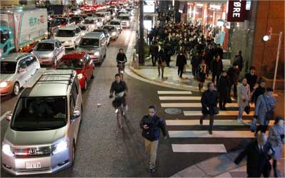 Residents walk between grid locked vehicles on their way home among chaotic traffic in central Tokyo