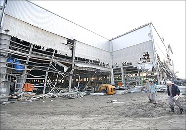 Workers walk past a damaged shipyard in an area hit by an earthquake and tsunami in Kuji.