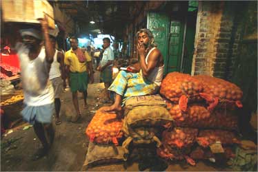 A potato seller smokes outside his shop at a vegetable wholesale market in Kolkata.