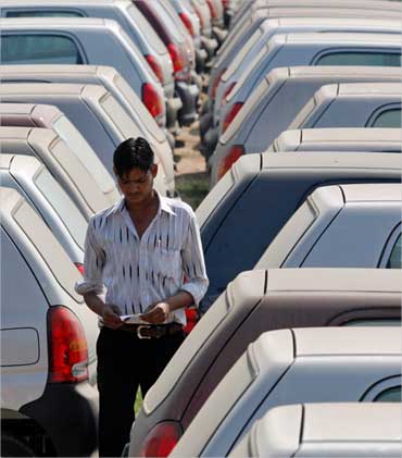 An employee walks between parked cars at Maruti Suzuki's stockyard on the outskirts of Ahmedabad.