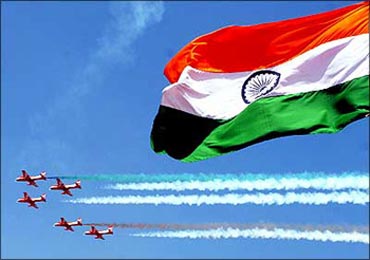 The Indian flag flutters as Indian Air Force jets fly by.