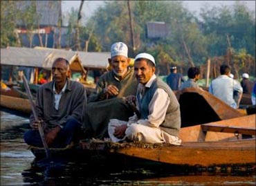 Kashmiris sitting by the Dal Lake on a shikara.