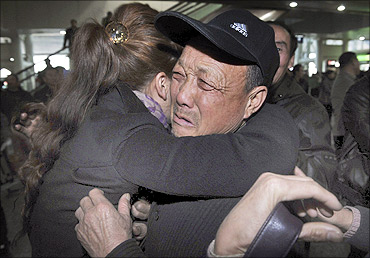 A man cries as he hugs his daughter who arrived on a flight from Tokyo.