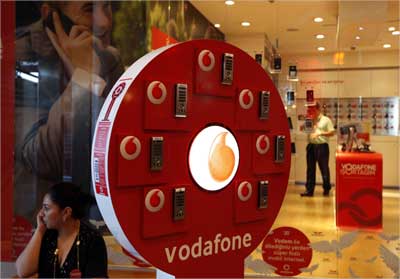A woman talks on her mobile phone in front of a Vodafone store at Vodafone Turkey headquarters in Istanbul.