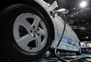 A Toyota Prius hybrid car is plugged into an electric outlet