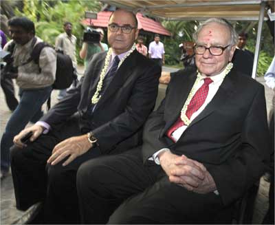 Buffett (R) sits in a golf cart with Eitan Wertheimer, chairman of ISCAR Metalworking.