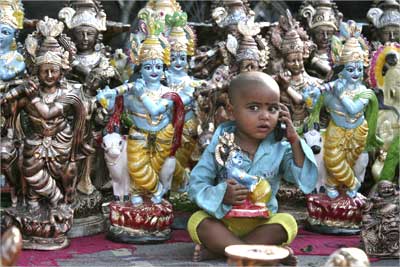 The son of an idol vendor plays with a mobile phone.
