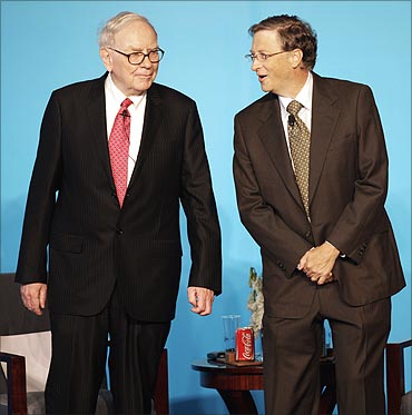 Bill Gates (R) talks to Warren Buffett.