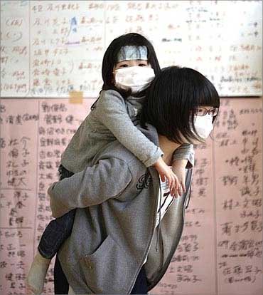 Owada Yuna carries her three-year-old sister Yumeka as she searches for names missing friends.