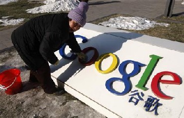 A woman cleans the logo of Google China outside the company headquarters in Beijing