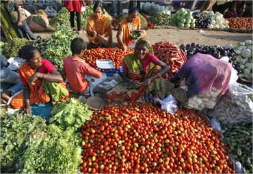 Vendors sell vegetables at an open air fruit and vegetable market.