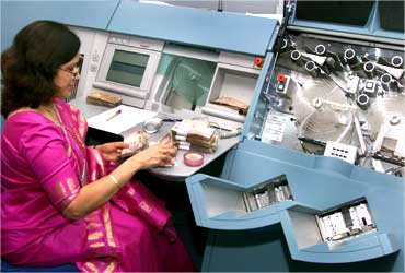 A RBI employee counts currency notes before placing them into new machines.