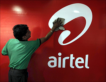 A worker cleans a Bharti Airtel logo.