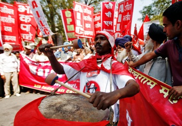 A CPI-M activist beats a drum at a rally against rising prices.