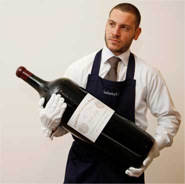 An employee poses with an 18 litre melchior of Chateau Cheval Blanc.