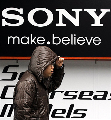 A man walks past a Sony logo in front of an electronic shop.