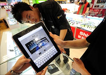 A shop assistant (L) displays an iPad at an electronic products store in Hefei.
