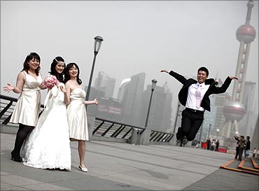 A wedding party pose for pictures with the Oriental Pearl TV Tower in the background.