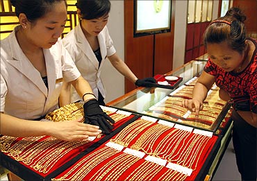 A customer selects gold jewellery from a glass case at a jewellery shop in Huaibei.