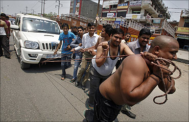 Supporters of Bharatiya Janata Party pull a vehicle with ropes.
