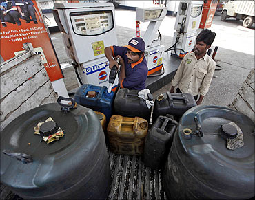 A worker fills plastic containers with diesel at a fuel station in Kolkata.