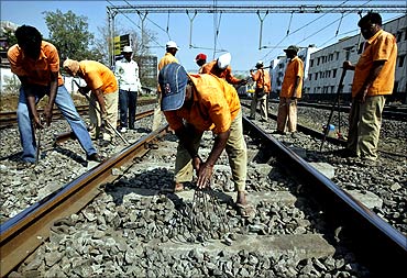 Employees of the Indian railways work on railway tracks.