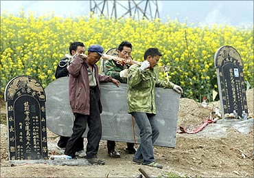 Workers carry a tombstone at a public cemetery.
