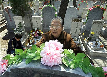 A woman places flowers on the tomb of a relative at Babao Cemetery in Beijing.