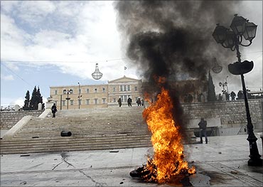 A police motorcycle is on flames in front of the parliament during riots in Athens.