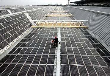 Workers work on a set of solar panels on the rooftop of the Nanjing South Railway Station Nanjing.