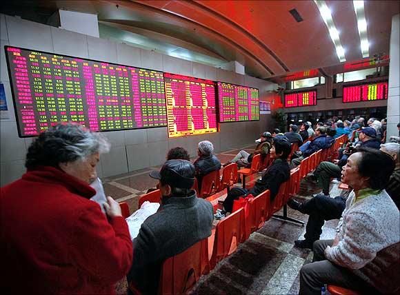 People look at an electronic board at a brokerage house in Shanghai.