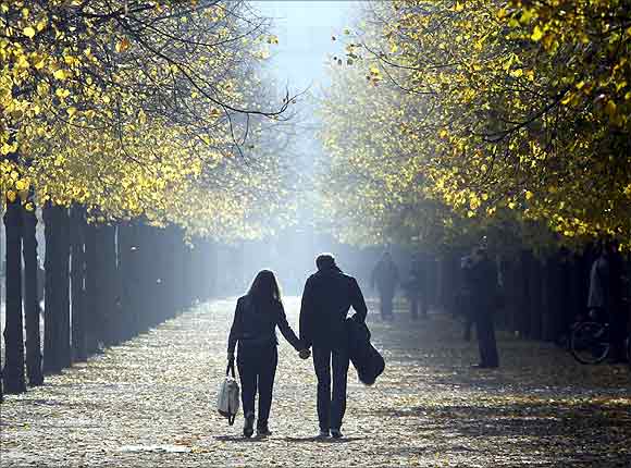 People walk in an allee near the Brandenburg Gate during a sunny day in Berlin.