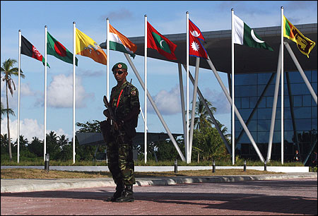 A Maldives army soldier stands guard near the flags of the SAARC countries in Addu.