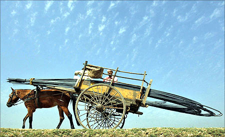 People transport iron rods on a horsecart to a construction site of a residential complex on the outskirts of Jammu.
