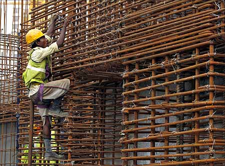 A worker climbs to fasten iron rods together at the construction site of a high-rise building in central Mumbai.