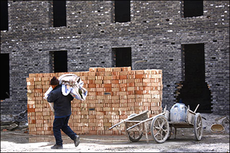 A worker carries blankets as he walks in front of a block of apartments under construction in Beijing.