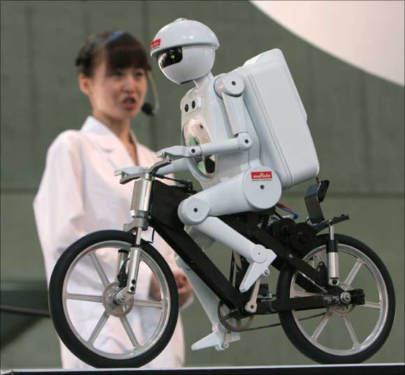 Humanoid robot Seisaku-kun pedals a bicycle during a demonstration at the Combined Exhibition of Advanced Technologies (CEATEC) in Makuhari, northeast of Tokyo.