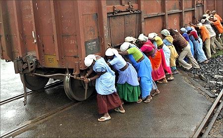 Railway workers push a wagon loaded with coal.