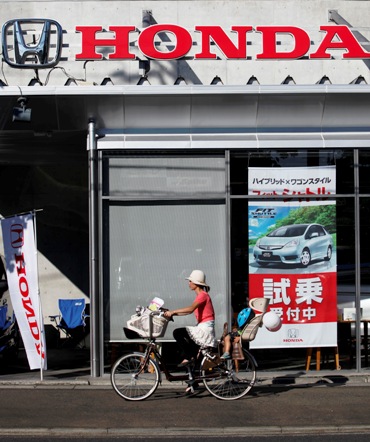 A woman cycles past a Honda dealer in Kawasaki, south of Tokyo