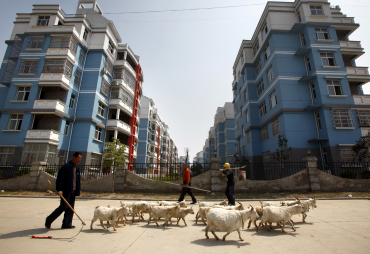 Construction workers walk past a farmer near newly constructed  buildings in Gushi, Henan Province.