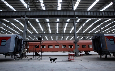 A dog walks past unfinished rail bogies in a rail coach factory in Rae Bareilly.