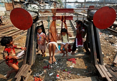 Children play on improvised swings made of cloth hung from a buffer stop near railway tracks in Mumbai.