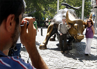 Tourists pose with the Charging Bull sculpture in Bowling Green park, near Wall Street, in New York.