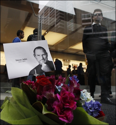 Customers leave an Apple Store as flowers in memory of Apple co-founder Steve Jobs.