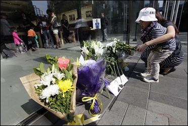 Flowers and a photograph of Steve Jobs are placed against the window outside the Apple store in Boston.