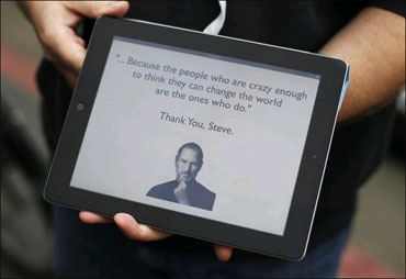 An Apple employee holds an iPad with its screen showing a message in memory of Jobs outside the store in San Francisco, California.