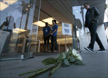 People walk into the Apple Store past roses left for Jobs in Santa Monica, California.