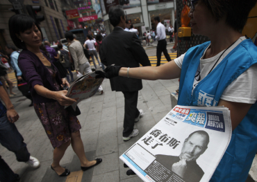 Workers hand out copies of a special edition of the Sharp Daily bearing the headline 'Steve Jobs Passed Away' in Hong Kong.