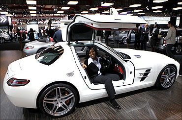 A visitor poses for a photograph in a Mercedes Benz SLS AMG GT3 sports car.
